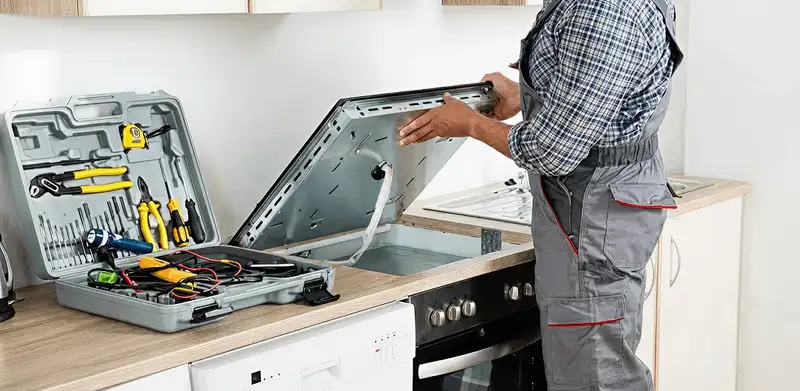 Handyman repairing a cooktop and checking wiring connections in Syracuse, NY