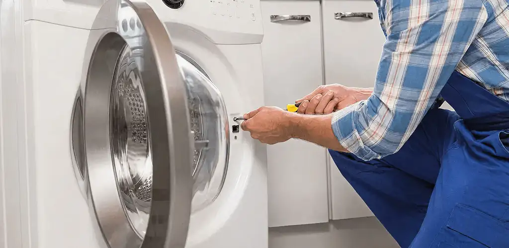 Handyman repairing a clothes dryer and checking electrical connections in Syracuse, NY