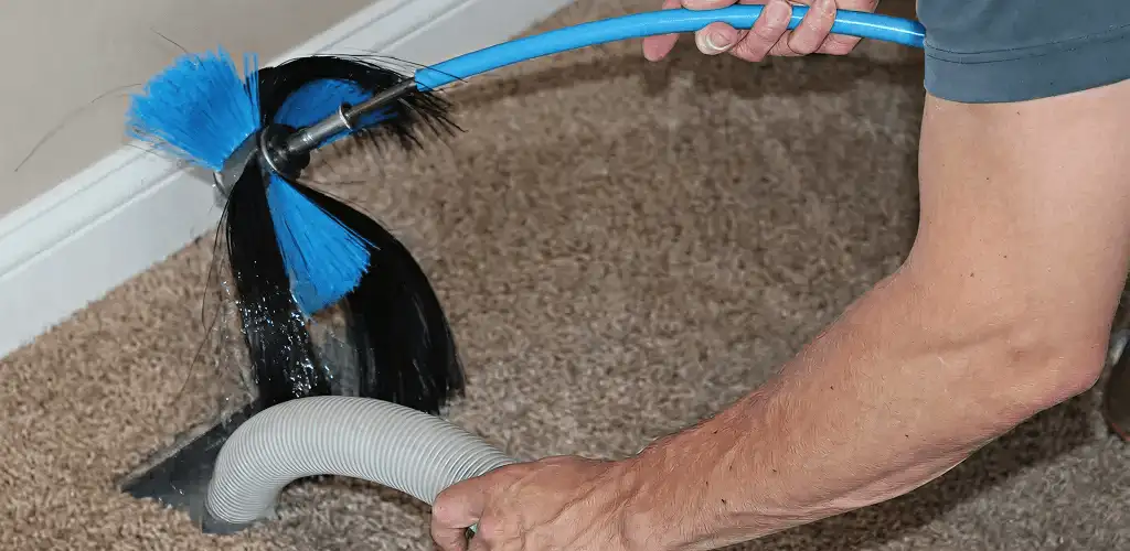 Dryer vent cleaning technician brushing lint from a vent line in Syracuse, NY