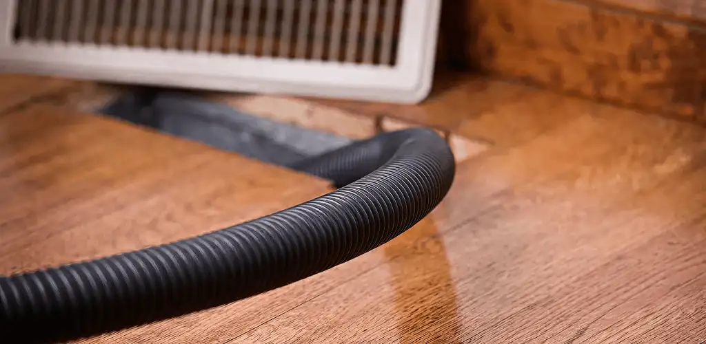Air duct cleaning hose inserted into a floor vent for ductwork cleaning in Syracuse, NY