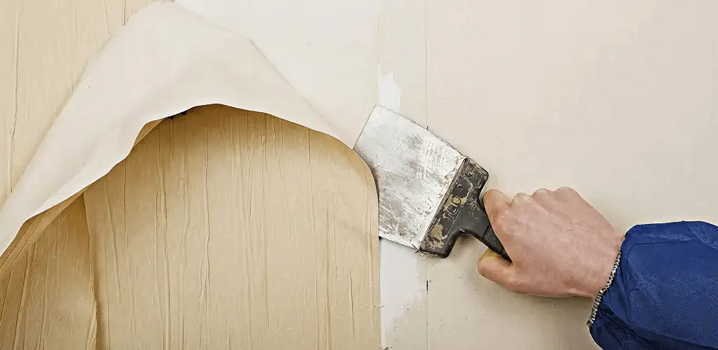 Handyman removing wallpaper with a scraper for wall preparation in Syracuse, NY