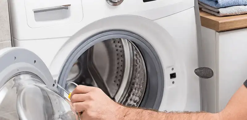 Handyman repairing a front-load washing machine and inspecting the drum in Syracuse, NY