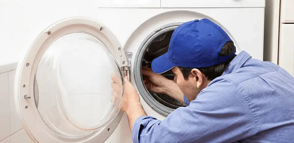 Washing machine repair handyman inspecting a front-load washer drum in Syracuse, NY