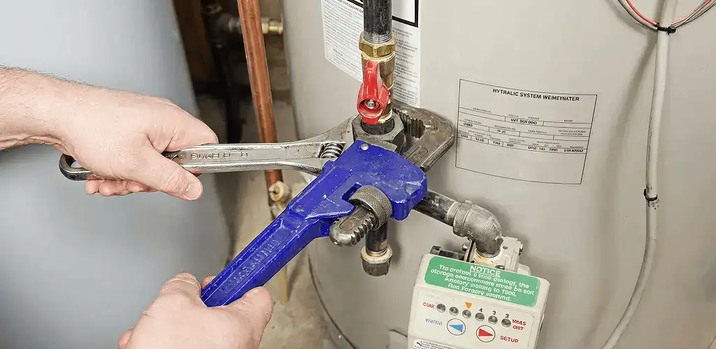 Water heater repair technician tightening the shutoff valve and supply line in Syracuse, NY